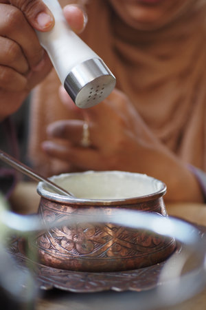 Adding seasoning to a traditional dish in a cozy settingの写真素材
