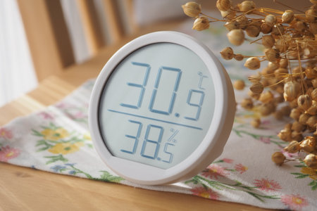 Indoor temperature and humidity monitor on a wooden tableの写真素材