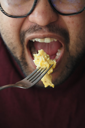 Enjoying a delicious bite of scrambled eggs at breakfastの写真素材
