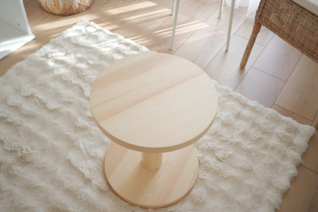Modern wooden table placed on soft rug in bright roomの写真素材