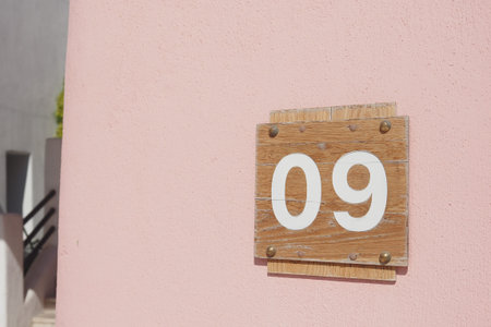 Wooden sign displaying number 09 on a pink wall