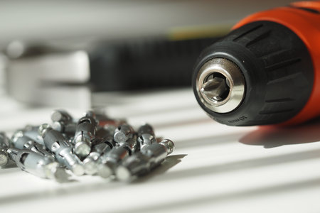Close-up of a power drill and screws on a work surfaceの写真素材
