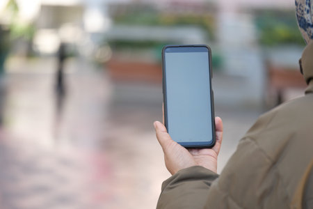 Person using smartphone in a busy outdoor locationの写真素材