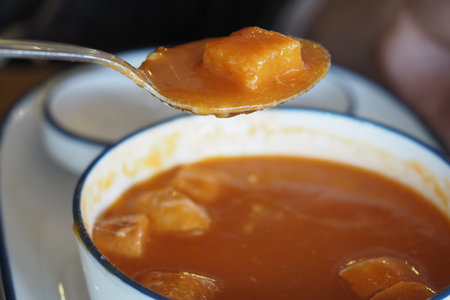Warm pumpkin soup with diced vegetables served in bowlの写真素材