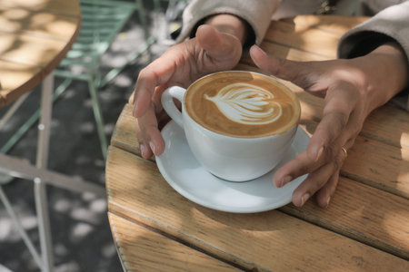 Enjoying a latte with beautiful latte art outdoorsの写真素材