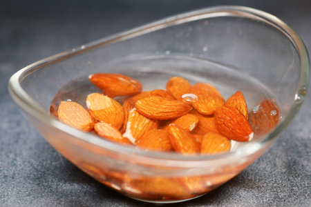 Soaked almonds in a glass bowl on dark surfaceの写真素材
