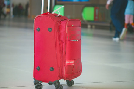 Bright red suitcase at the airport terminal. lost luggage conceptの写真素材