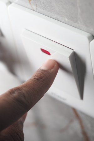 Finger pressing light switch in modern interior settingの写真素材