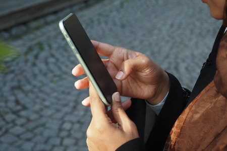 Person using smartphone outdoors in a city settingの写真素材