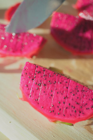 Slicing vibrant dragon fruit on a wooden boardの写真素材
