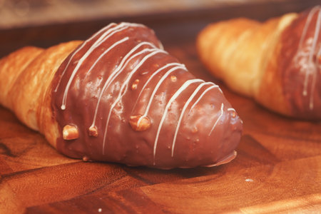 Delicious chocolate-coated croissant on wooden boardの写真素材