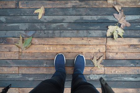 Footsteps on a wooden walkway with autumn leavesの写真素材