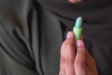 Woman holds green lip bum in a close-up shotの写真素材