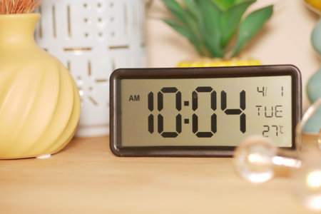A digital clock shows 10:04 AM on a Tuesday in a warm roomの写真素材