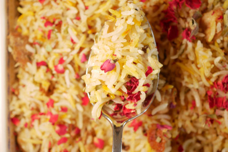Colorful biryani served in a large spoon with rose petalsの写真素材