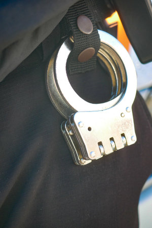 Handcuffs hanging from a police belt in an urban settingの写真素材