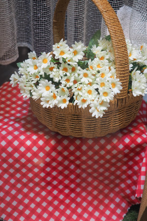 Flower basket on a red checkered tablecloth near a windowの写真素材