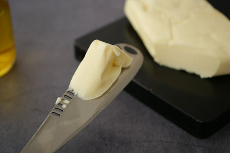 Butter being spread with a knife on a dark cutting boardの写真素材