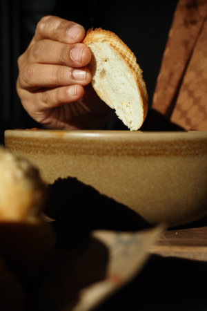 Enjoying warm bread with savory dip in cozy settingの写真素材