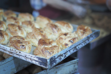 Freshly baked pastries on a metal tray in a bakeryの写真素材