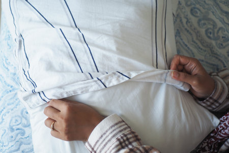 Pillowcase being adjusted on a cozy bedの写真素材