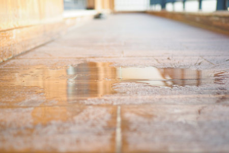 Wet floor reflecting light in a sunlit corridorの写真素材