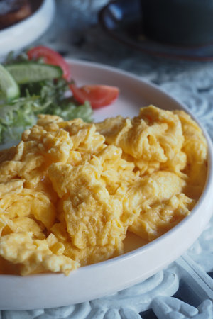 Fluffy scrambled eggs served with fresh saladの写真素材