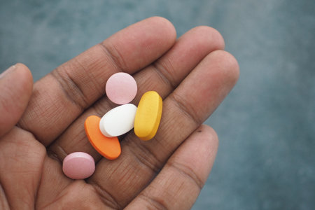 Hand holding various colorful pills for health and wellnessの写真素材