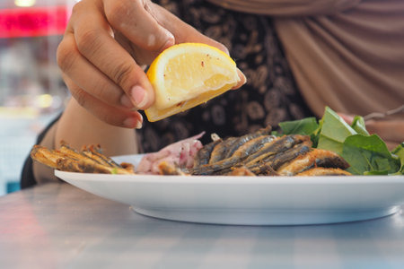 Enjoying grilled fish with lemon at a seaside restaurantの写真素材