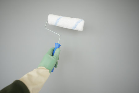 Painting a wall with a roller in a light gray colorの写真素材