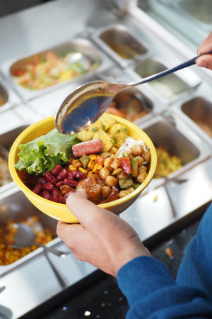 Creating a colorful bowl of mixed ingredients at a salad barの写真素材