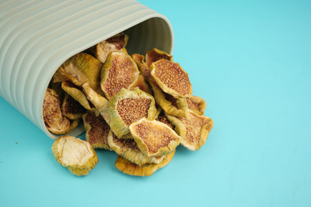 Dried figs spilling from a container on a blue background