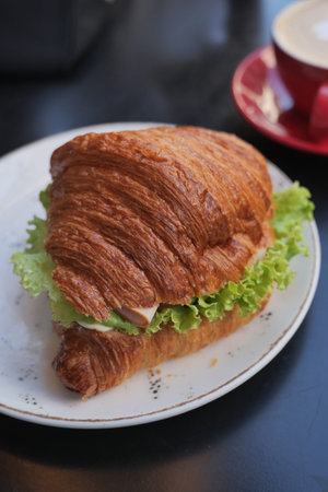 Fresh croissant sandwich with lettuce served in cafeの写真素材