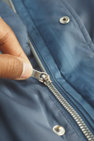 Hand zipping a blue jacket in a casual setting