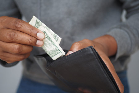 Hands placing money into a black wallet during a transaction