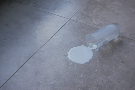 Milk spills on a tiled floor during breakfast timeの写真素材