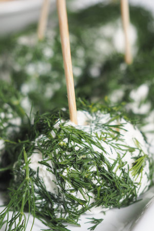 Herb-covered cheese balls served with skewers for tasting