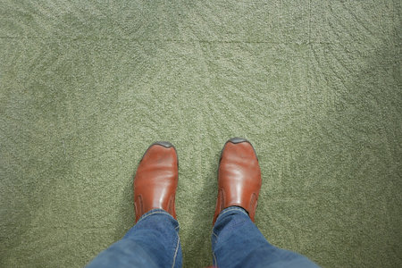 Brown shoes on green carpet while standing indoorsの写真素材
