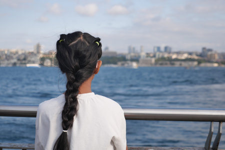 Girl looking at city skyline by the water