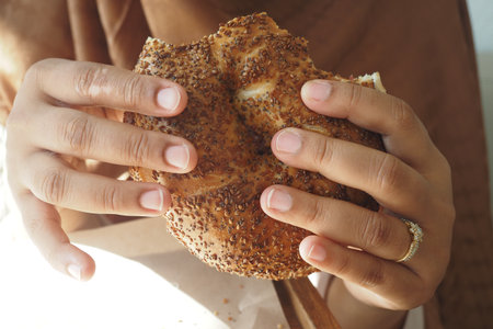 Eating a sesame-coated bread roll with both handsの写真素材