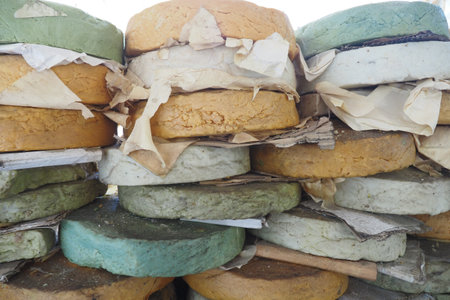 Colorful cheese rounds stacked at a market in the afternoonの写真素材