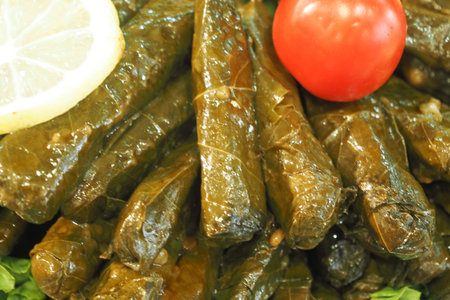 Stuffed grape leaves with lemon and tomato garnishの写真素材