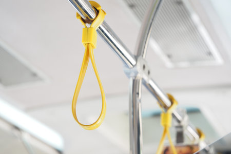 Yellow hanging strap inside a bus during daytime commuteの写真素材