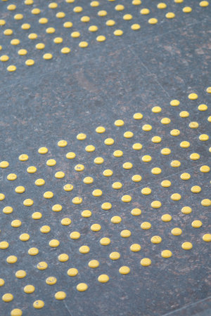 Yellow tactile paving dots on sidewalk provide guidance