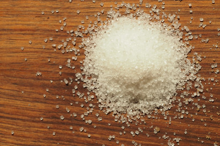 White sugar granules scattered on wooden surfaceの写真素材