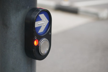 Pedestrian signal button at urban crosswalk during daytime