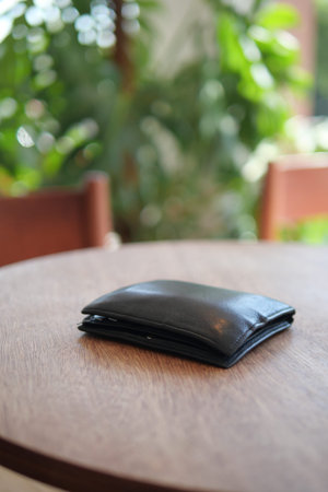 Black wallet resting on a wooden table.lost wallet concept.