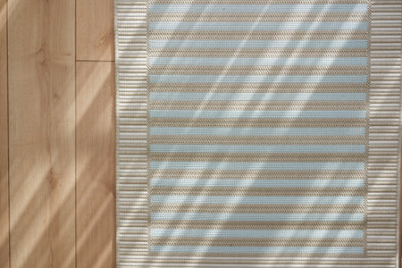 Sunlight creating patterns on woven rug in bright interiorの写真素材