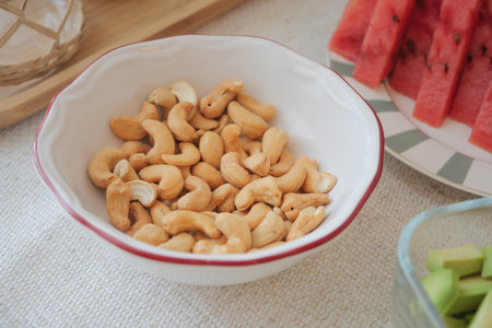 Cashews in a bowl next to fresh fruit platterの写真素材