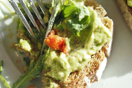 Fresh avocado toast with greens and tomato on whole grain